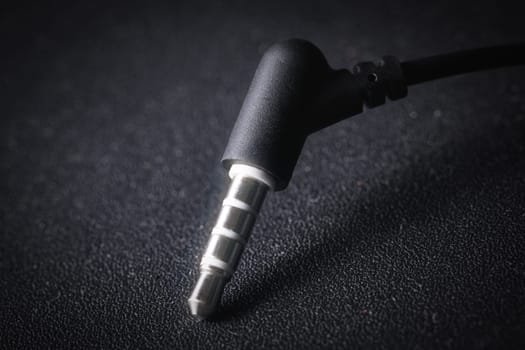 Audio Mini Jack plug on black background, metal glowing in the light, close-up macro photography