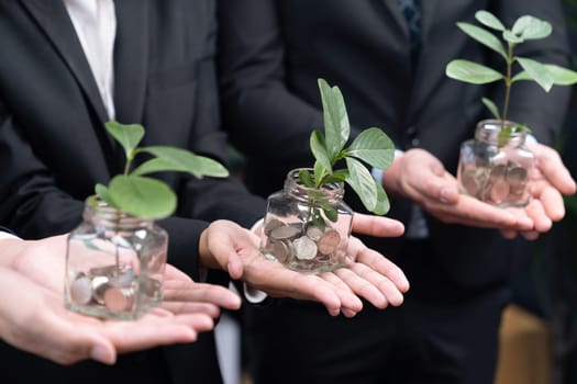 Business people holding money savings jar filled with coins and growing plant for sustainable financial planning for retirement or eco subsidy investment for environment protection. Quaint