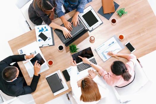 Top view of businessman executive in group meeting with other businessmen and businesswomen in modern office with laptop computer, coffee and document on table. People corporate business team uds