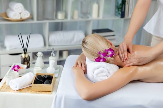 Caucasian woman customer enjoying relaxing anti-stress spa massage and pampering with beauty skin recreation leisure in day light ambient salon spa at luxury resort or hotel. Quiescent