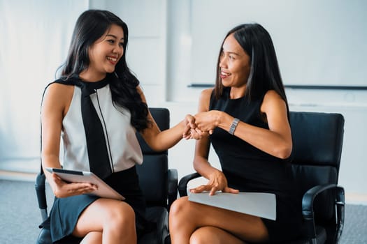 Two young Asian businesswomen do handshake in office. Business friends and community concept. uds