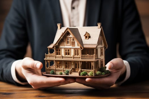 A model of a house in the hands of a man in a business suit. The concept of purchasing, building housing.