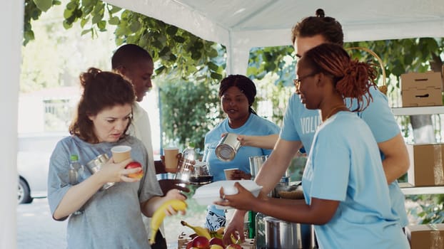 Warm meals are given to the underprivileged by humanitarians through a non-profit organization. Volunteers distributing free food and essentials to the needy during an outdoor food drive. Tripod shot.