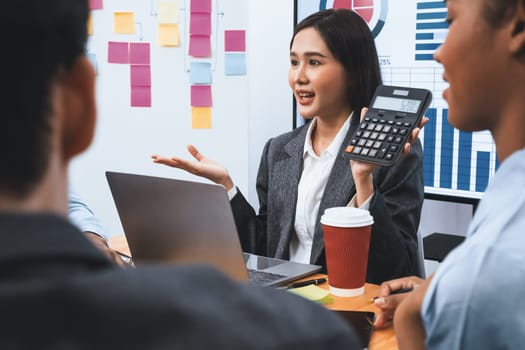 Multiracial analyst team use calculator and data science BI Fintech dashboard data to analyze financial report on office meeting table. Diverse business people for analytic teamwork. Concord