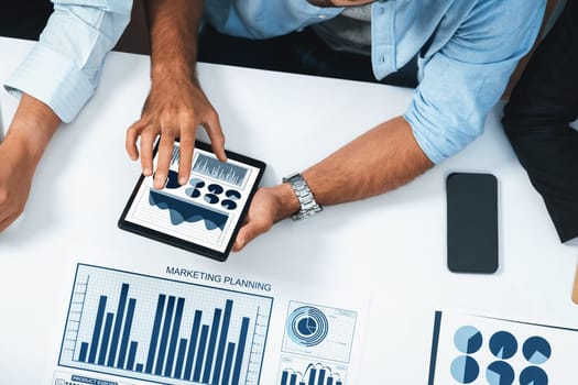 Top view analyst team utilizing BI Fintech to analyze financial data at table in meeting room. Analytic BI dashboard power on paper for business insight and strategic marketing planning. Prudent