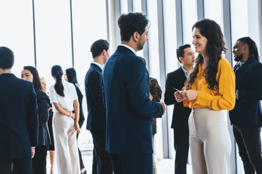 Businessman discussing with female leader about financial project intentionally while standing rounded with business people exchanging financial experience. Side view. Office hallway. Intellectual.