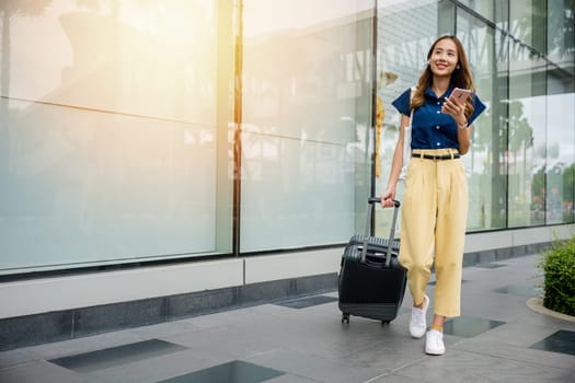 With her luggage in tow, a young black woman makes her way through the city, using her mobile phone to keep her connected while on vacation.