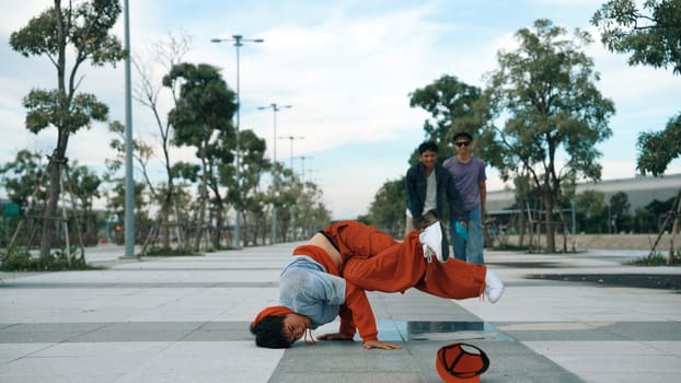Attractive hipster doing b-boy dancing with multicultural friend. Professional handsome break dancer doing freeze pose while enjoy b-boy dancing. Modern lifestyle. Outdoor sport 2024. Sprightly.