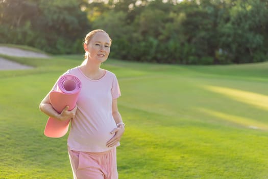 Energetic pregnant woman takes her workout outdoors, using an exercise mat for a refreshing and health-conscious outdoor exercise session.