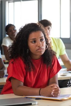 Vertical portrait of female black college students in classroom listening to lecture. Highschool black girl student in class. Education concept.