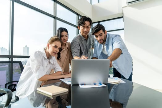 Asian project manager uses laptop displayed data analysis while professional business team brainstorming marketing idea at business meeting. Working together,sharing idea, planing strategy. Tracery.