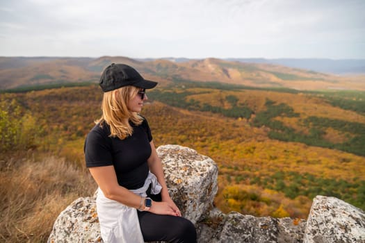 woman on mountain peak looking in beautiful mountain valley in autumn. Landscape with sporty young woman, blu sky in fall. Hiking. Nature.