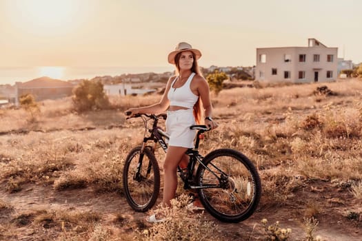 A woman cyclist on a mountain bike looking at the landscape sea. Adventure travel on bike