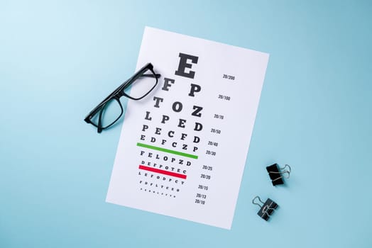 Eye test chart and glasses on blue background