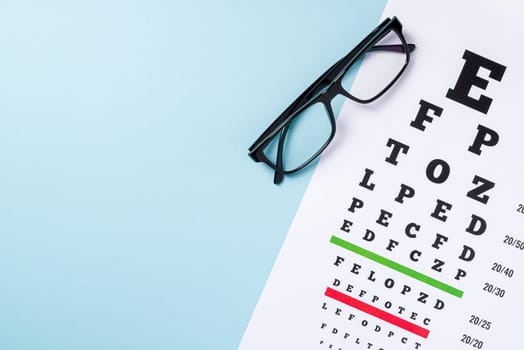 Eye test chart and glasses on blue background