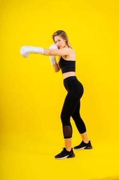 Woman boxer in gloves training on a yellow and dark studio background
