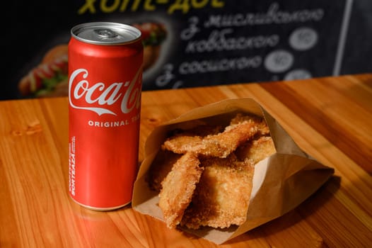 Ivano-Frankivsk, Ukraine March 26, 2023: Coca Cola and fried chicken nuggets on the table, a quick snack in a cafe.