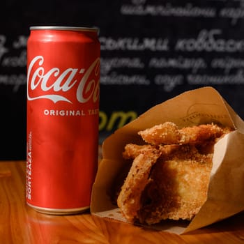 Ivano-Frankivsk, Ukraine March 26, 2023: Coca Cola and fried chicken nuggets on the table, a quick snack in a cafe.