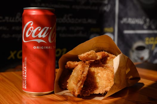 Ivano-Frankivsk, Ukraine March 26, 2023: Coca Cola and fried chicken nuggets on the table, a quick snack in a cafe.