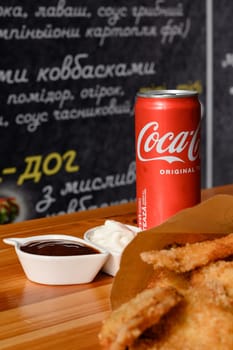 Ivano-Frankivsk, Ukraine March 26, 2023: Coca Cola and fried chicken nuggets on the table, a quick snack in a cafe.