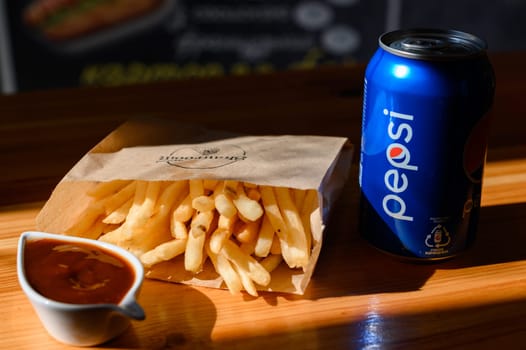 Ivano-Frankivsk, Ukraine March 26, 2023: Pepsi and french fries in a paper bag on a black background.