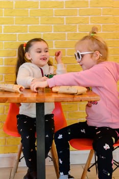 Ivano-Frankivsk, Ukraine March 26, 2023: Two little girls eat hotdogs in a cafe, junk food for children.