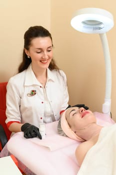 Ivano-Frankivsk, Ukraine, May 17, 2023: a girl at a cosmetolon undergoing a carboxytherapy procedure, a cosmetologist demonstrates a facial beauty product, cosmetology procedure.