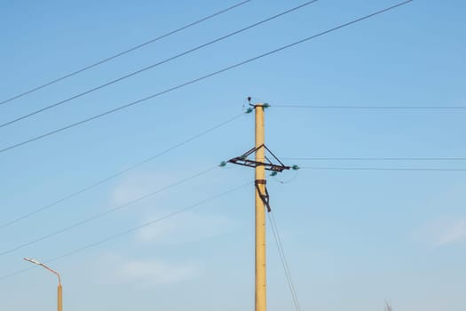 A pole with electric wires against a blue sky, copy space