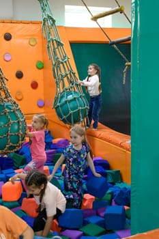 Ivano-Frankivsk, Ukraine June 7, 2023: A child rides on a rope over a pool of soft cubes, children's entertainment in a playroom.