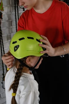 A little girl is put on a helmet as protection on the cable car, the cable car in the playroom. Ivano-Frankivsk, Ukraine June 7, 2023