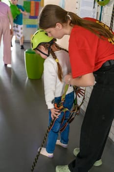 Ivano-Frankivsk, Ukraine June 7, 2023:A little girl is put on a helmet as protection on the cableway , the cable car in the playroom.