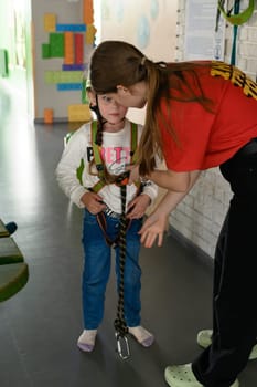 Ivano-Frankivsk, Ukraine June 7, 2023:A little girl is put on a helmet as protection on the cableway , the cable car in the playroom.