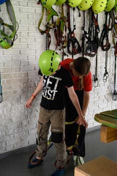 Ivano-Frankivsk, Ukraine June 7, 2023:A boy puts on a helmet and insurance before going on a cableway ride, a large playroom and a cable car in it.