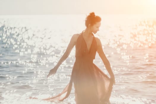 Side view a Young beautiful sensual woman in a red long dress posing on a rock high above the sea during sunrise. Girl on the nature on blue sky background. Fashion photo.