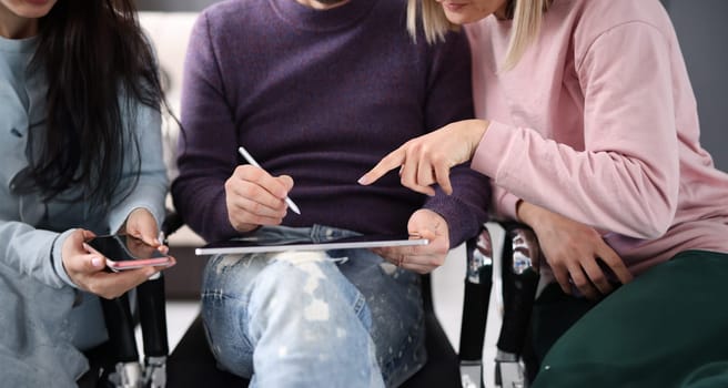 Employees point to tablet screen while discussing hot topics. Receiving information from electronic devices concept