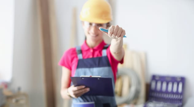 Smiling master builder holds pen and clipboard. Construction budgeting concept