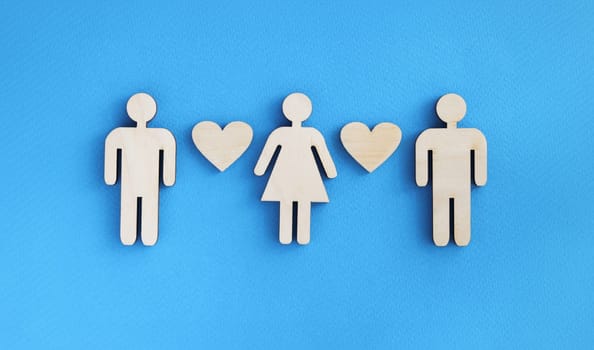 Wooden figurines of men and women with hearts on blue background. Love triangle in relationship concept