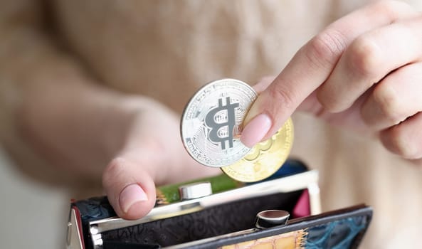Female hand putting bitcoins into wallet closeup. Cryptocurrency concept