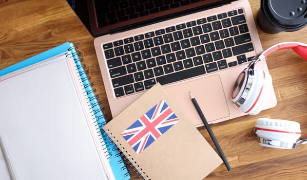 Headphones and english textbooks lying on laptop keyboard closeup. Learning foreign languages online concept