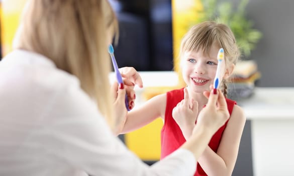 Little girl choosing toothbrush from doctors hands in clinic. Childrens dentistry concept