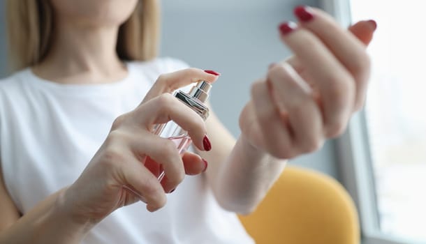 Young woman spraying perfume on her hand closeup. Body care concept