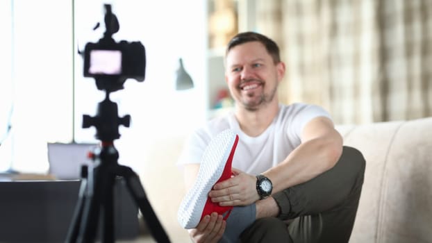 Young man taking pictures of sneakers on his feet closeup. Blogging freelance concept