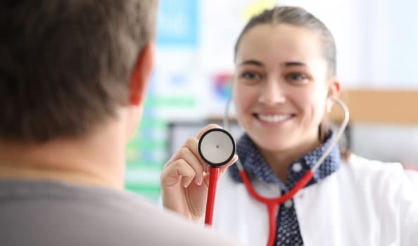 Woman doctor holding stethoscope in front of patient closeup. Medical consultation concept