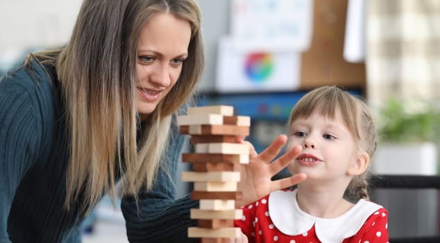 Young woman with daughter playing board game. Spending time together with child concept