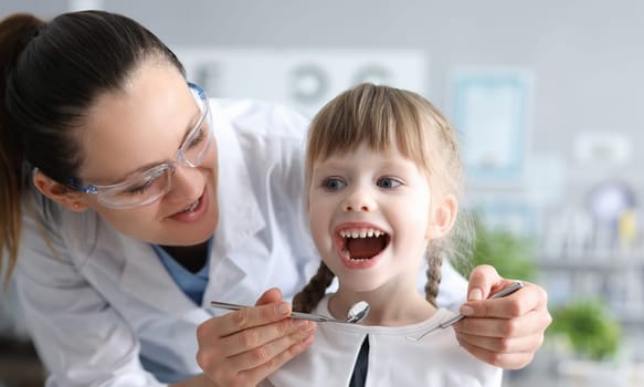 Dentist examining mouth of little girl with instruments. Preventive examination of oral cavity concept