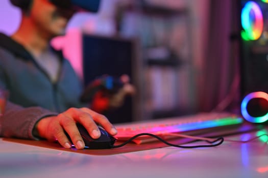 Close up of gamer holding mouse playing video game on computer at home. Gaming, esports and tournament concept