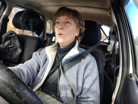 Terrified female driver a second before the accident. Scared middle-aged adult woman holds the steering wheel of car. Frightened Lady girl who is owner or rent a car for travel