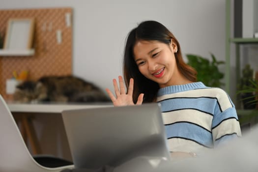 Smiling young woman enjoying pleasant conversation, making video call on laptop