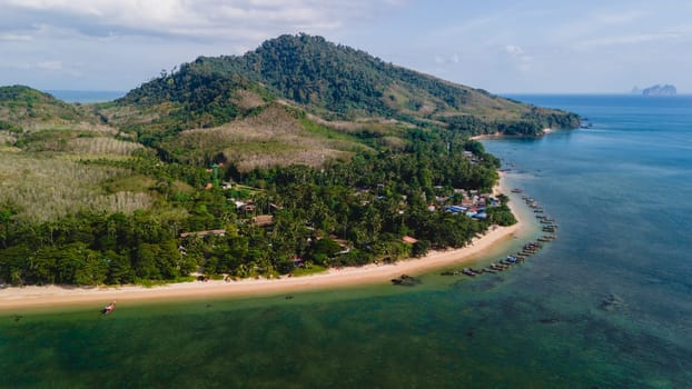 A beautiful view of a calm beach with crystal clear water on the blue sky at Koh Libong, Trang province, Thailand, Andaman Sea with mountains on the beackground