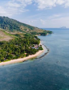 A beautiful view of a calm beach with crystal clear water on the blue sky at Koh Libong, Trang province, Thailand, Andaman Sea with mountains on the beackground